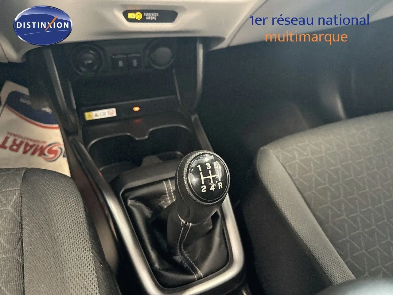 Gros plan sur le levier de vitesse manuel noir de la Suzuki Swift 1.2 Pack Hybrid 2024, intérieur tissu gris.