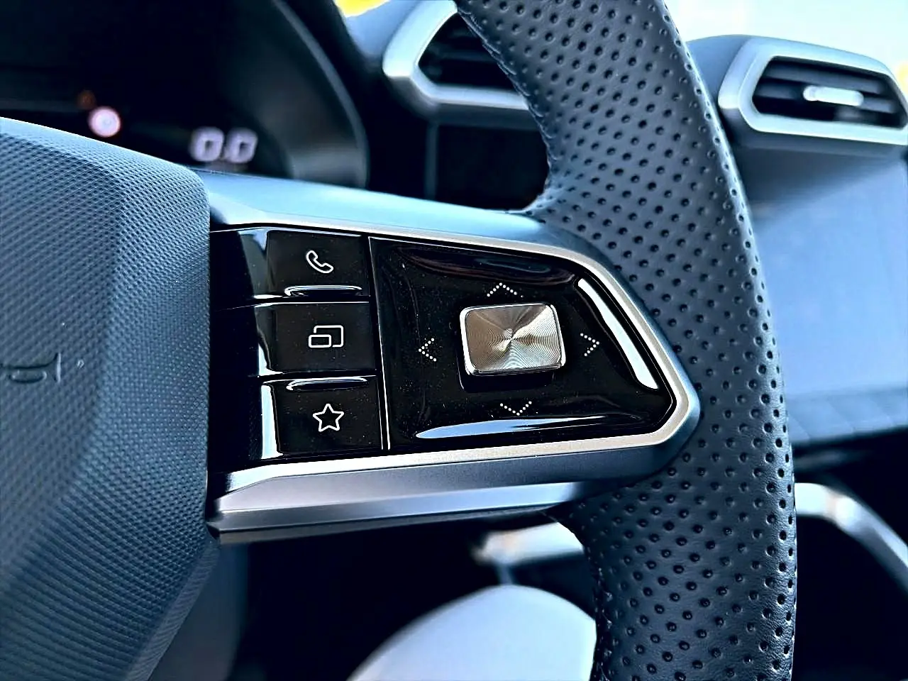 Gros plan sur les commandes multifonctions noires et argentées du volant perforé du MG Motor ZS hybride 2026.