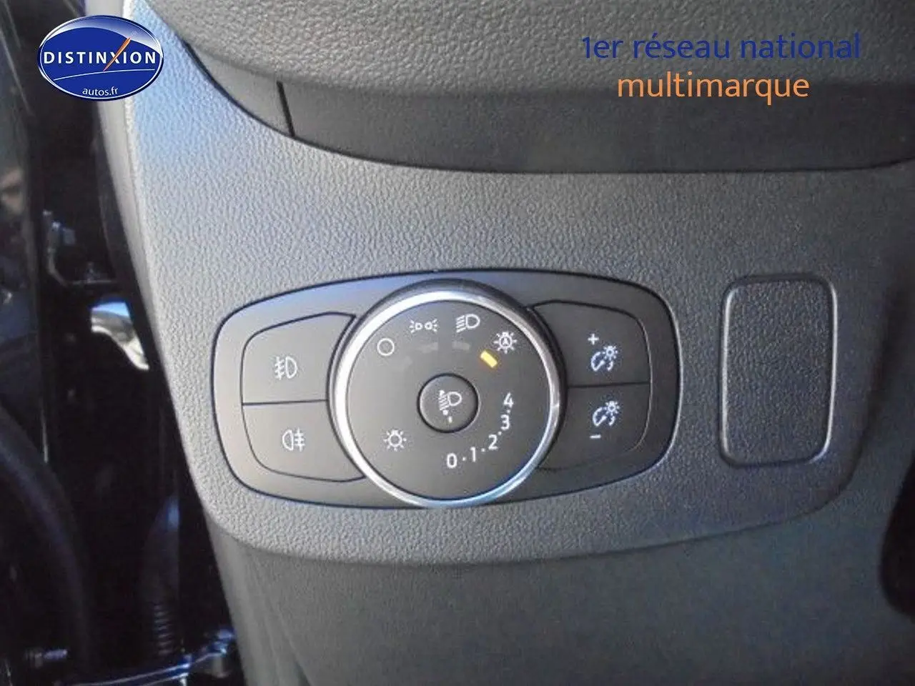 Gros plan sur le bouton de réglage des phares du Ford Puma 2022, tableau de bord en plastique noir texturé.