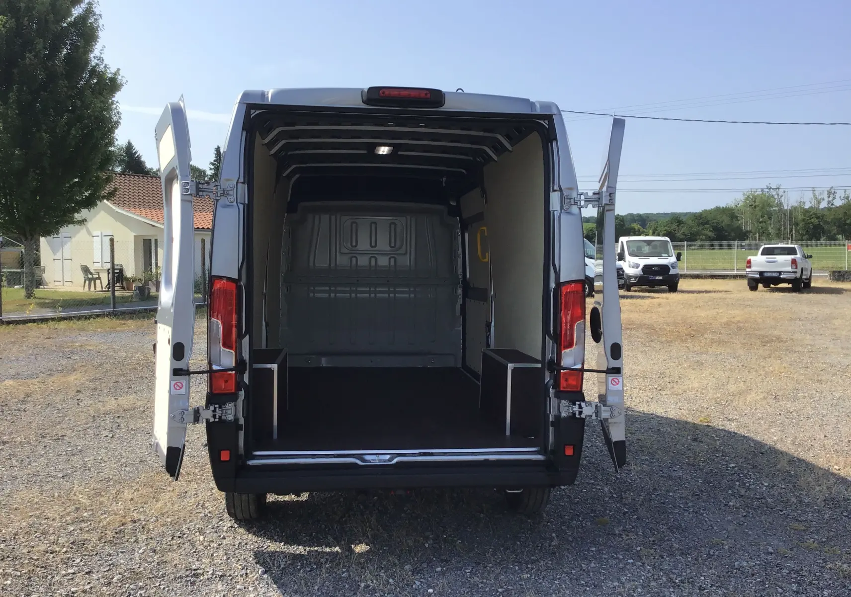Vue arrière du Peugeot Boxer Fourgon gris Artense 2025 avec portes ouvertes montrant l'espace de chargement vide.