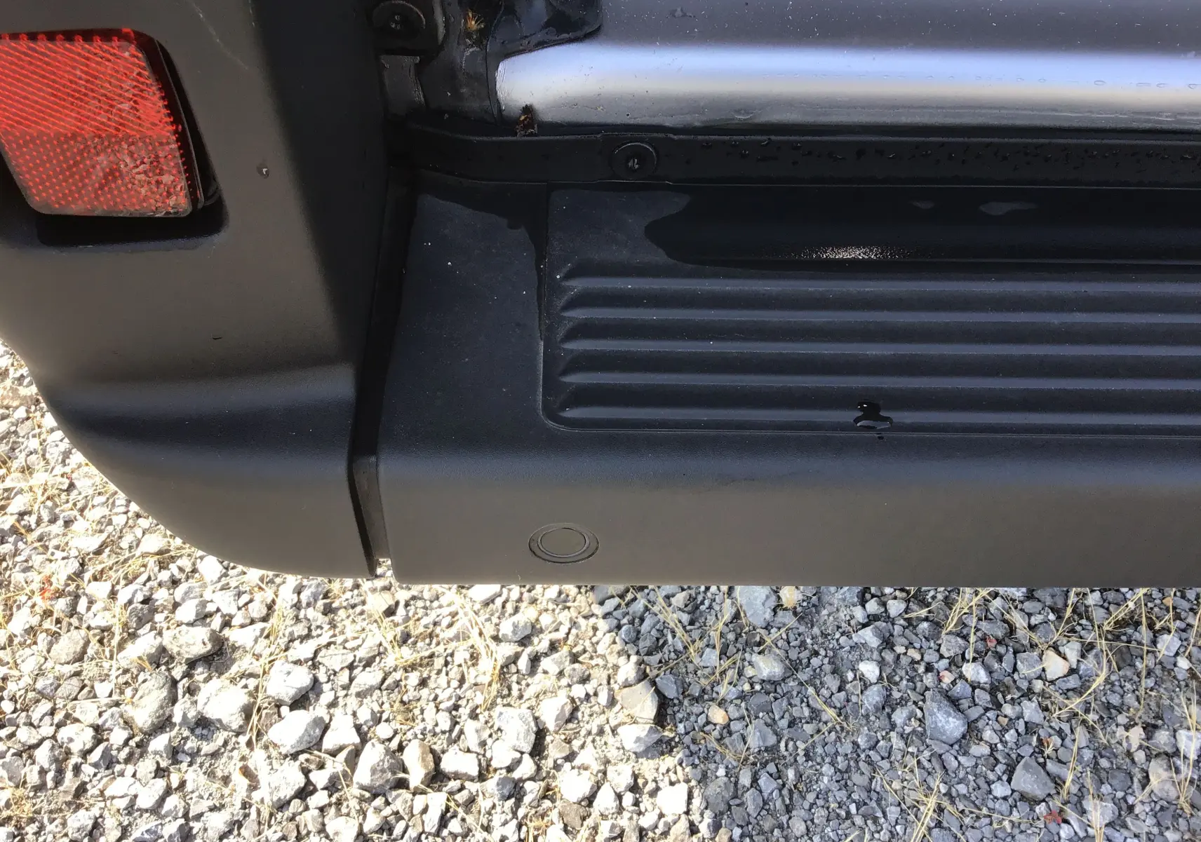 Gros plan sur l'angle arrière gauche du Peugeot Boxer Fourgon gris Artense, montrant le pare-chocs et le feu arrière.