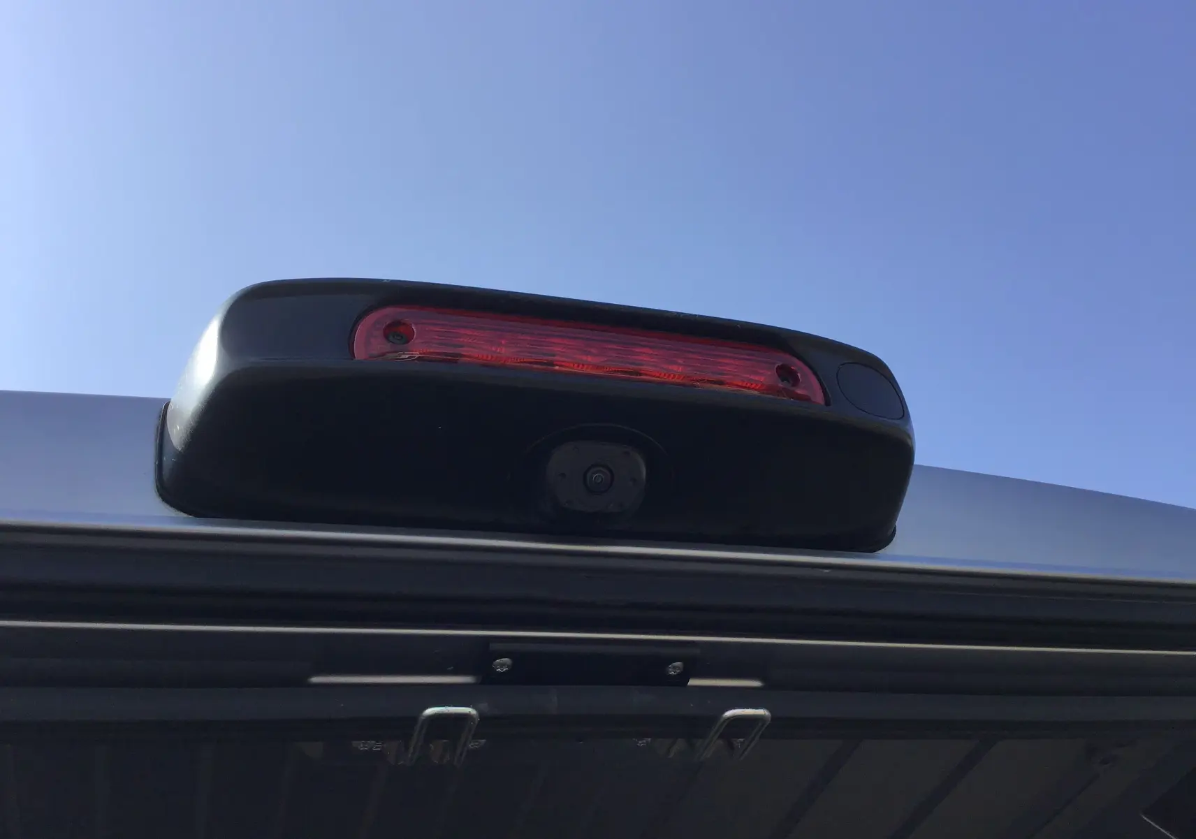 Gros plan sur le feu stop et la caméra de recul du Peugeot Boxer Fourgon gris Artense, vue arrière sous ciel bleu.