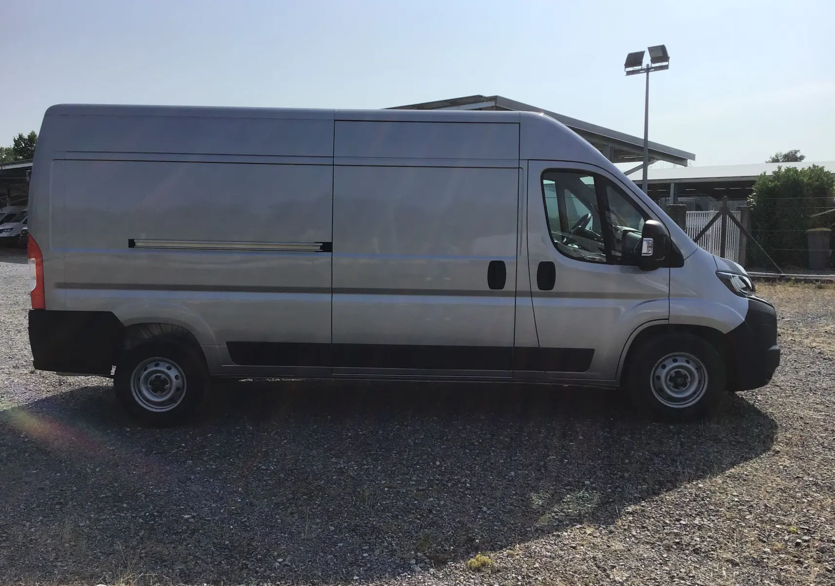 Vue latérale droite d'un Peugeot Boxer Fourgon gris Artense, avec porte coulissante et jantes acier simples.