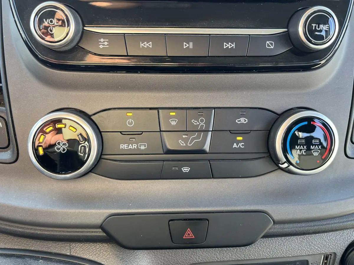 Vue rapprochée de la console centrale du Ford Transit Custom blanc 2021, montrant les commandes de climatisation et audio.