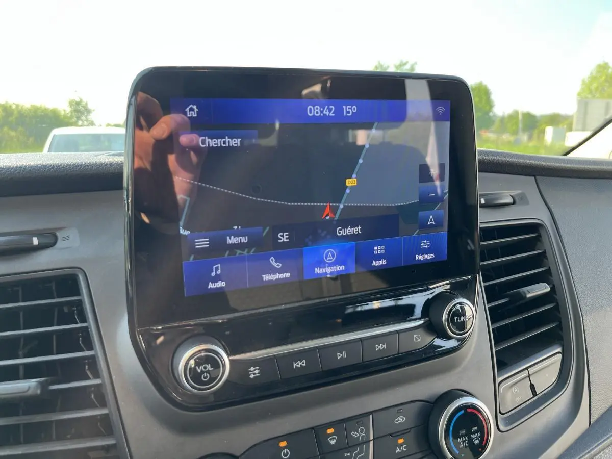 Écran tactile SYNC 3 avec navigation GPS visible sur le tableau de bord du Ford Transit Custom blanc.