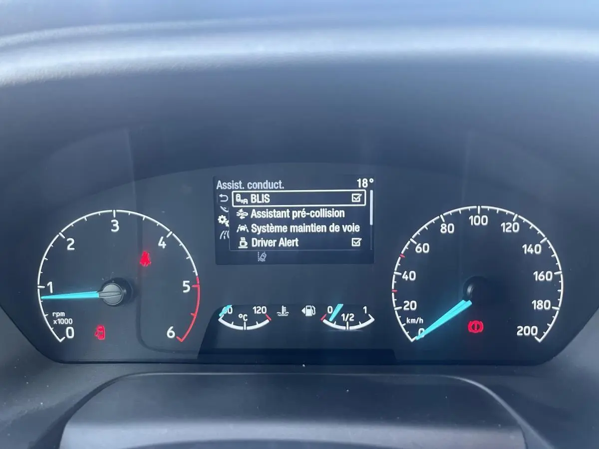 Tableau de bord du Ford Transit Custom blanc 2021 montrant les compteurs et l'écran d'assistance à la conduite.