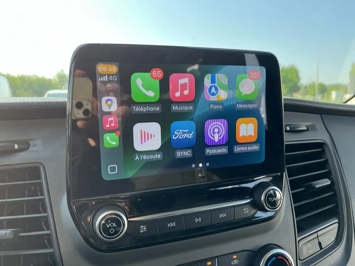 Écran tactile SYNC 3 au tableau de bord du Ford Transit Custom blanc, vue rapprochée de la console centrale.