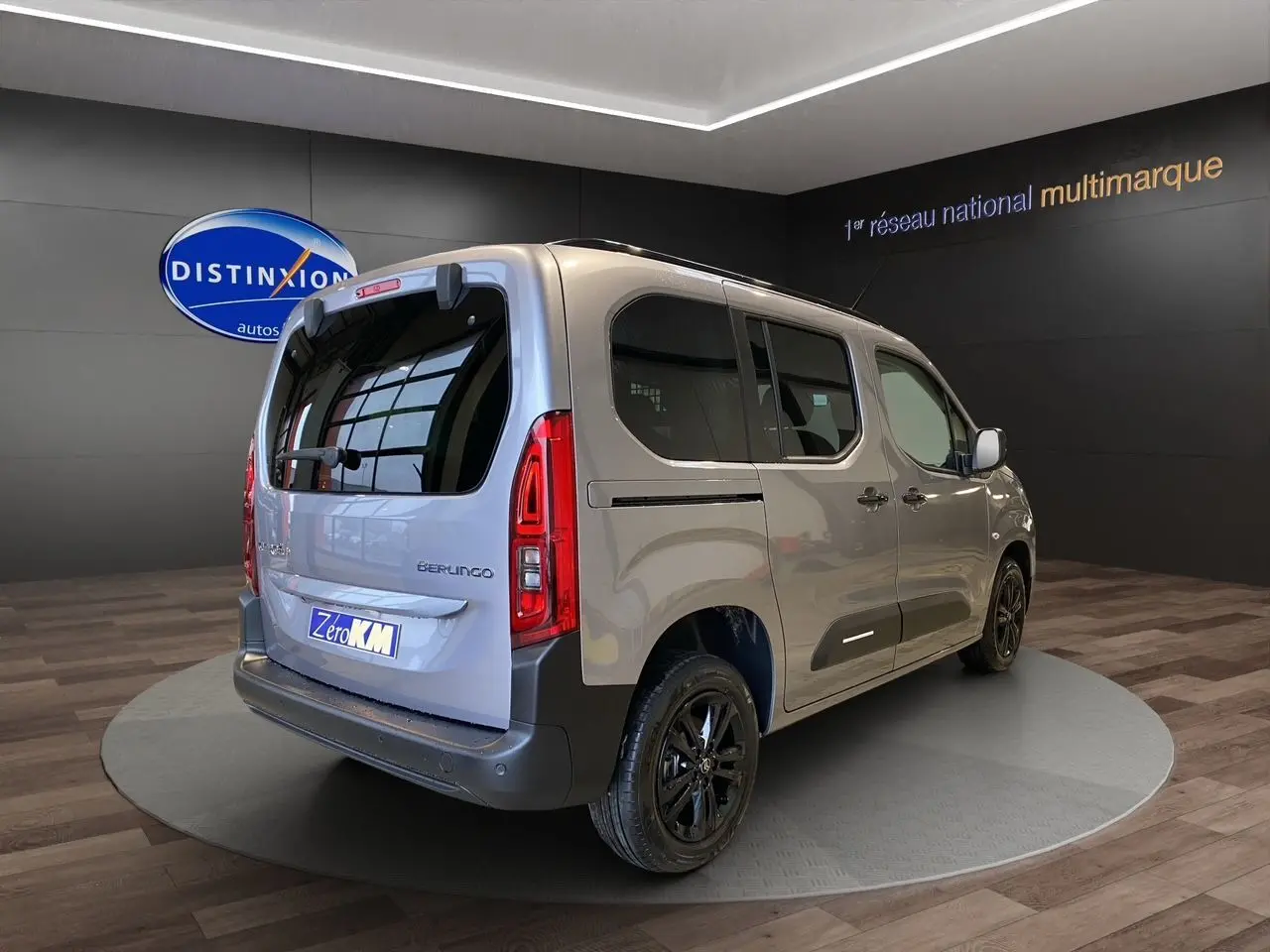Vue 3/4 arrière droit du Citroën Berlingo gris Artense avec jantes noires et vitres teintées en showroom.