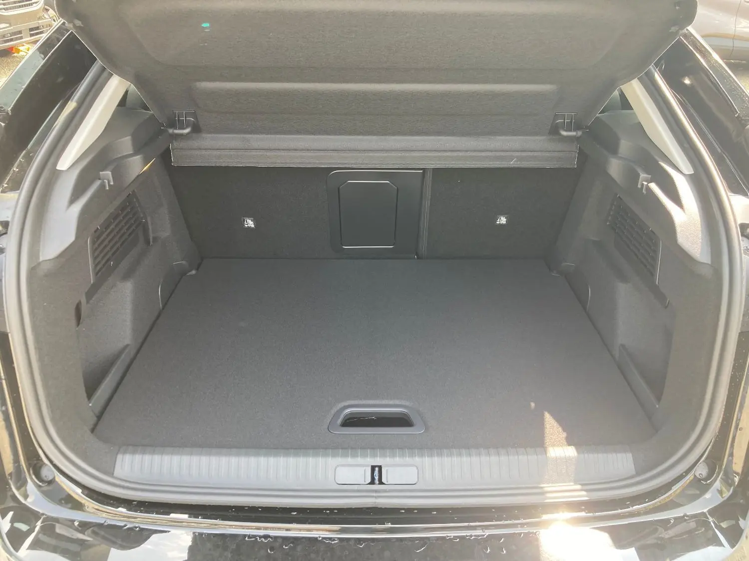 Coffre ouvert d'une Citroën C4 noir perla, montrant un espace de chargement propre et bien fini.