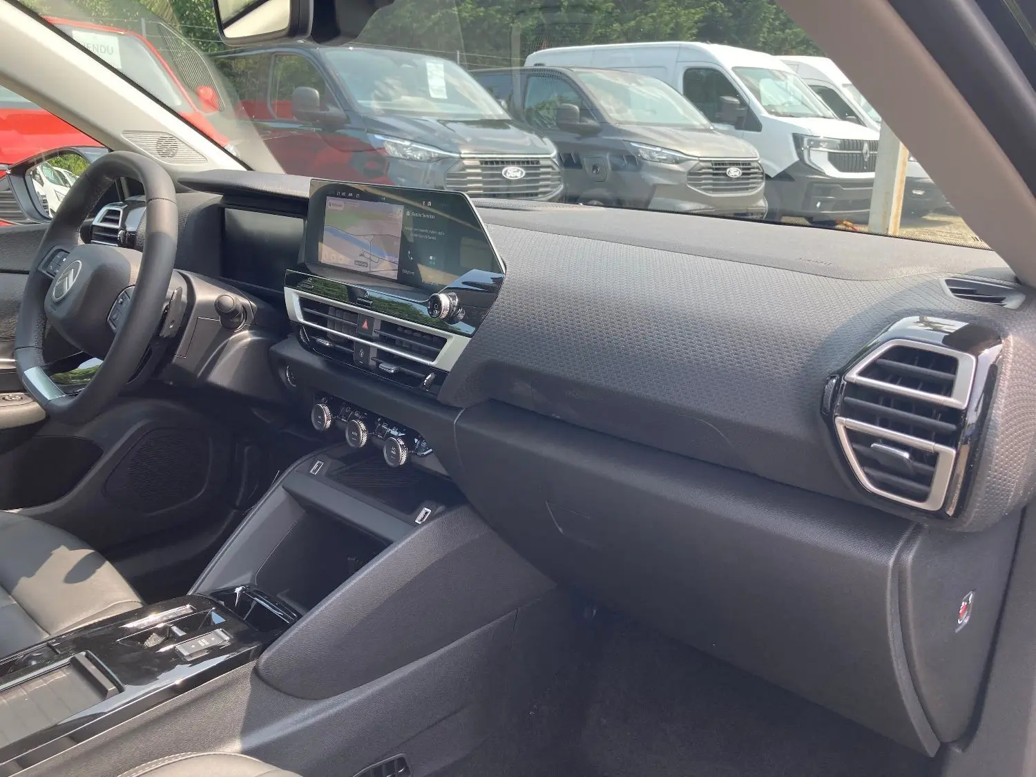 Vue intérieure côté passager du tableau de bord et console centrale du Citroën C4 Facelift Hybrid 2025 en noir Perla.