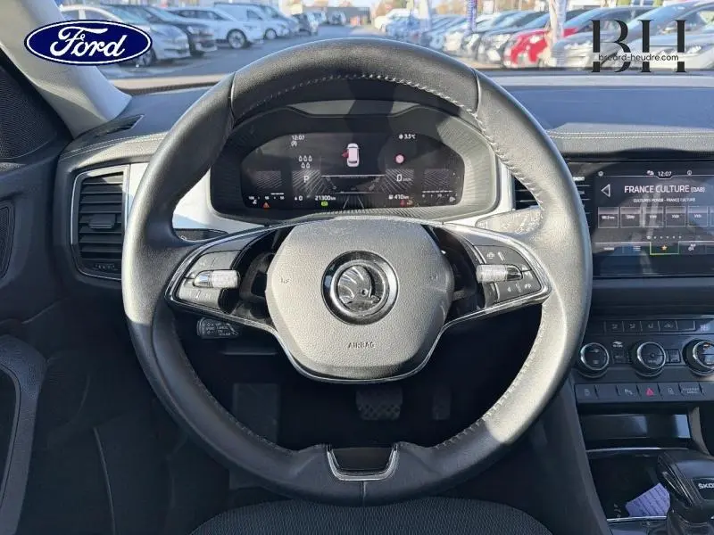 Vue centrée sur le volant cuir multifonction noir du Skoda Kodiaq 2023 avec tableau de bord numérique et écran tactile.