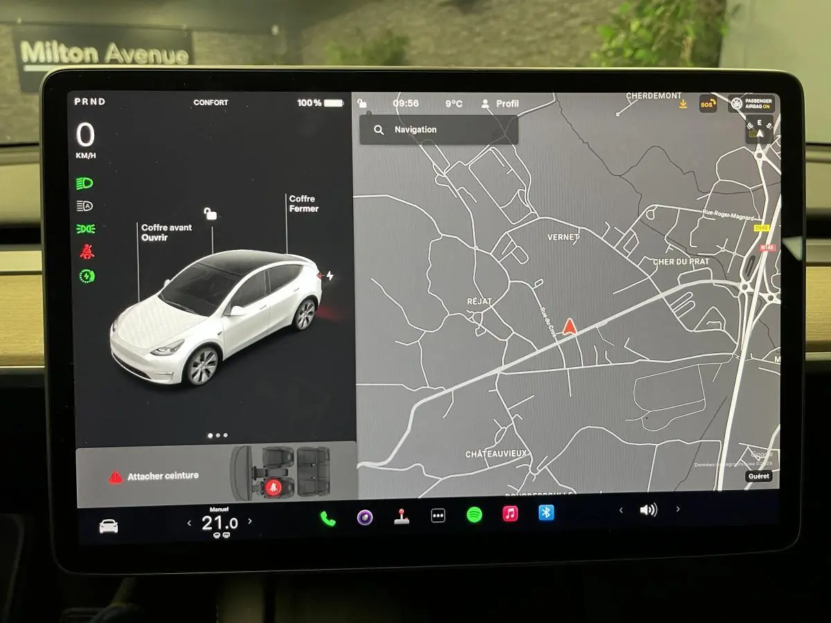 Écran tactile intérieur affichant la navigation et la Tesla Model Y blanche vue de 3/4 avant en simulation.