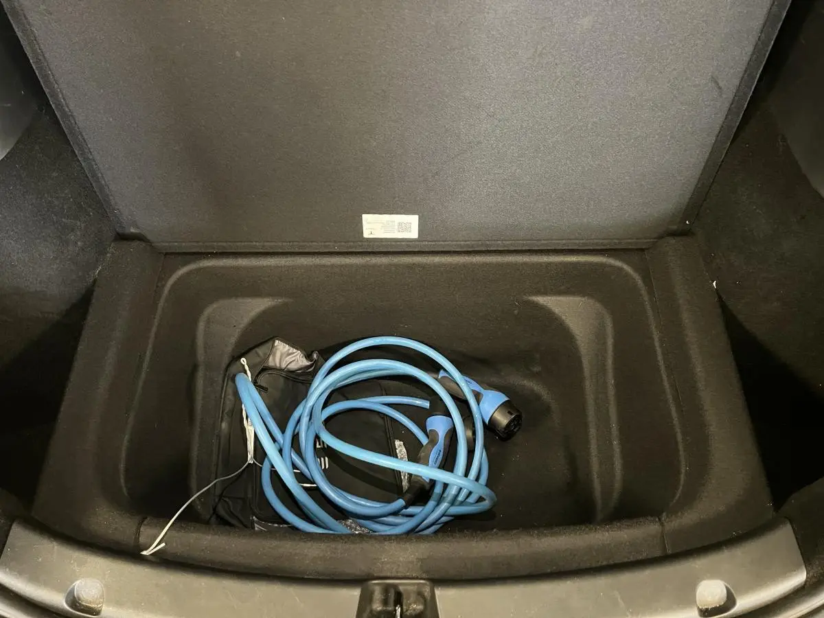 Coffre avant ouvert d'une Tesla Model Y blanc nacré 2022, montrant un câble de recharge électrique bleu enroulé.