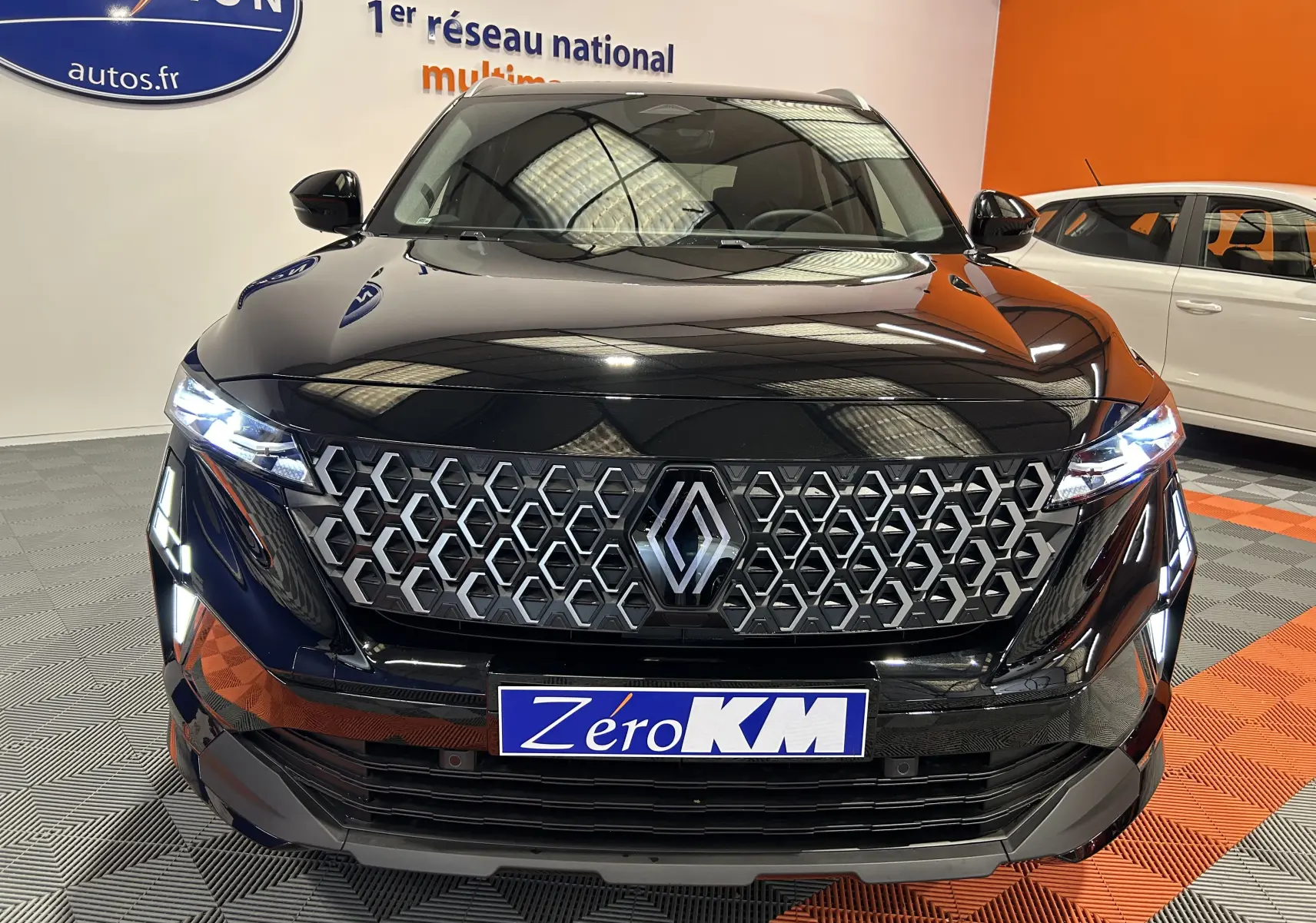 Renault Austral Ph.2 E-TECH noir étoilé, vue frontale mettant en valeur la calandre hexagonale et les phares LED allumés.