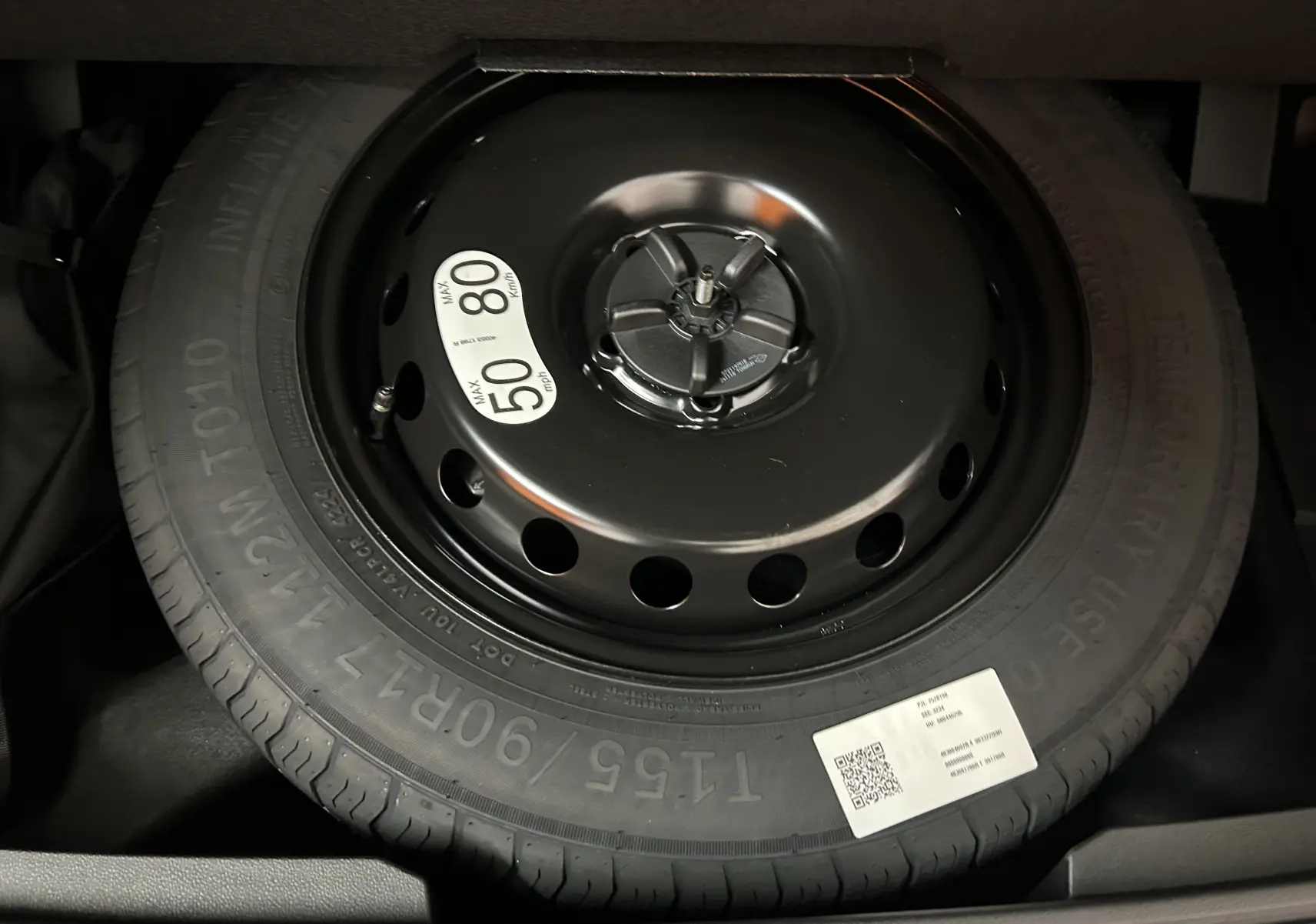 Gros plan sur la roue de secours noire avec étiquette de limitation de vitesse dans le coffre du Renault Austral 2025 noir étoilé.