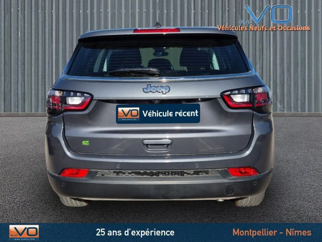 Vue arrière d'un Jeep Compass gris 2024 avec feux LED et logo distinctif sur un parking extérieur.