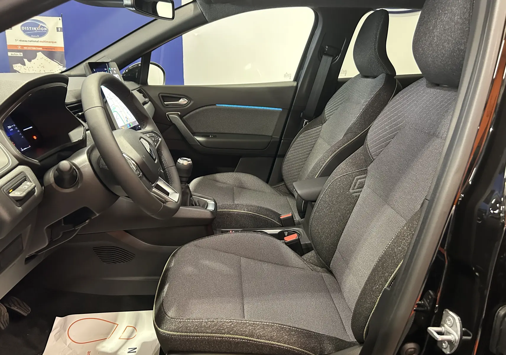 Intérieur avant du Renault Captur II Ph.2 TECHNO noir étoilé, sièges tissu gris avec surpiqûres jaunes et volant multifonction.