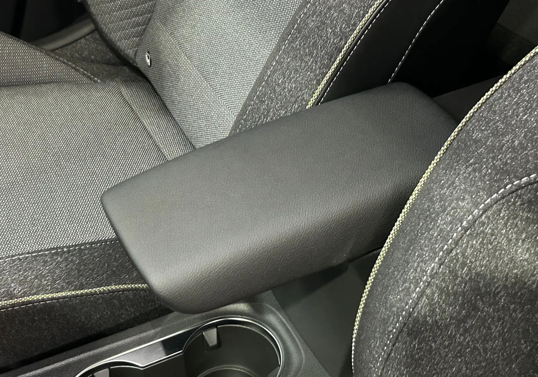 Accoudoir central en cuir noir et sièges tissu gris avec surpiqûres jaunes dans un Renault Captur II Ph.2 TECHNO.