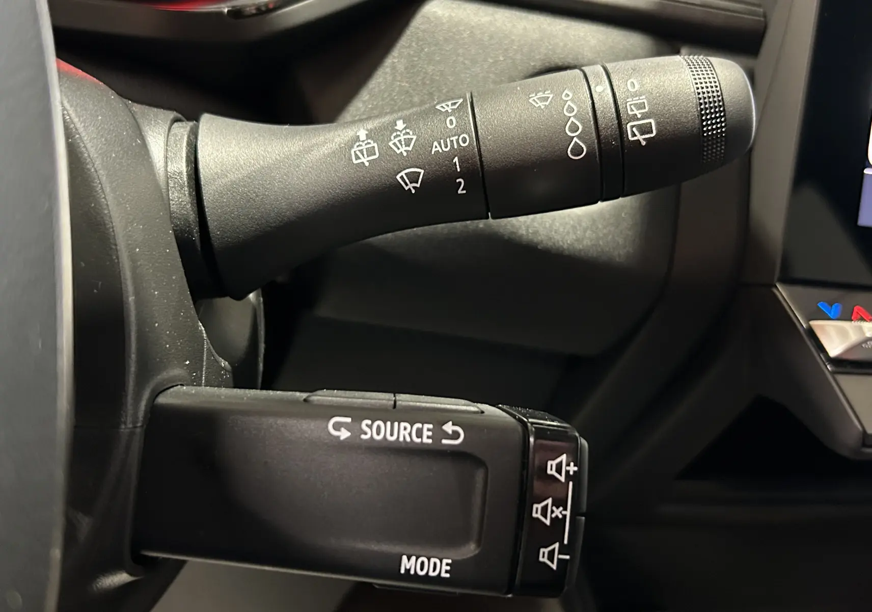 Gros plan sur les commandes de la colonne de direction du Renault Captur II Ph.2 TECHNO noir étoilé, boutons source et mode visibles.