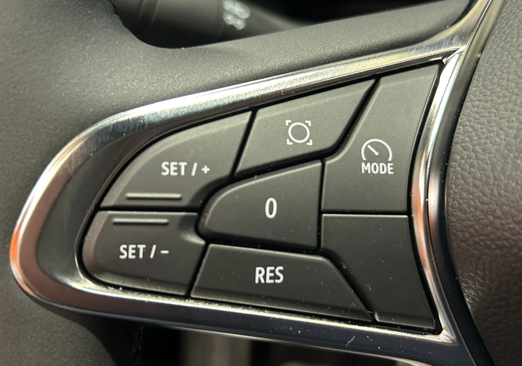 Gros plan sur les commandes de régulateur de vitesse du volant du Renault Captur II Ph.2 noir étoilé 2025.