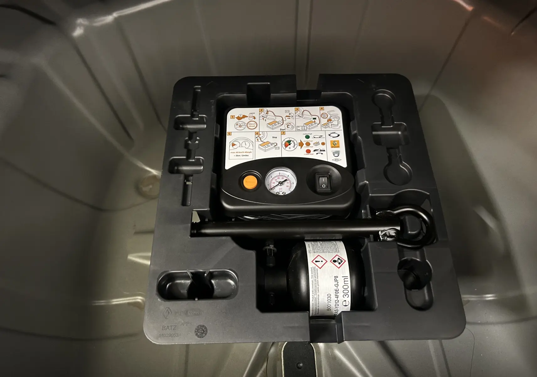 Gros plan sur le kit de réparation pneumatique dans le coffre du Renault Captur II Ph.2 TECHNO Tce 90 noir étoilé 2025.