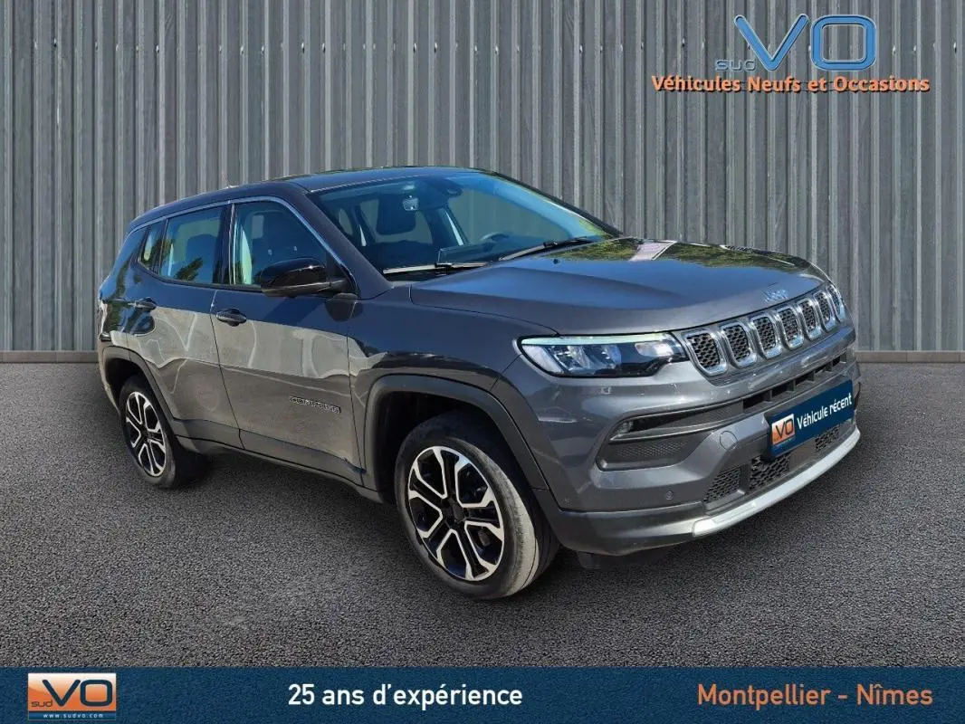 Jeep Compass gris 3/4 avant droit avec jantes alliage 18 pouces, stationné devant un mur métallique.