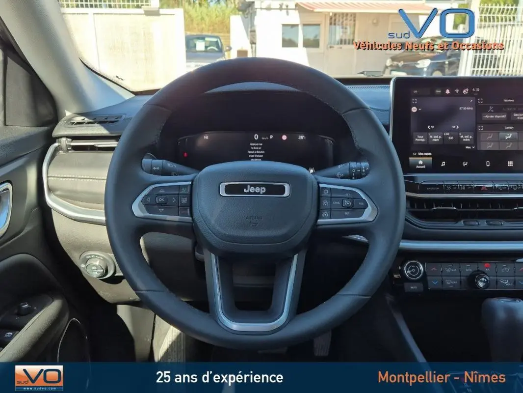 Vue frontale du volant et tableau de bord du Jeep Compass gris 2024 avec écran tactile et commandes au volant.