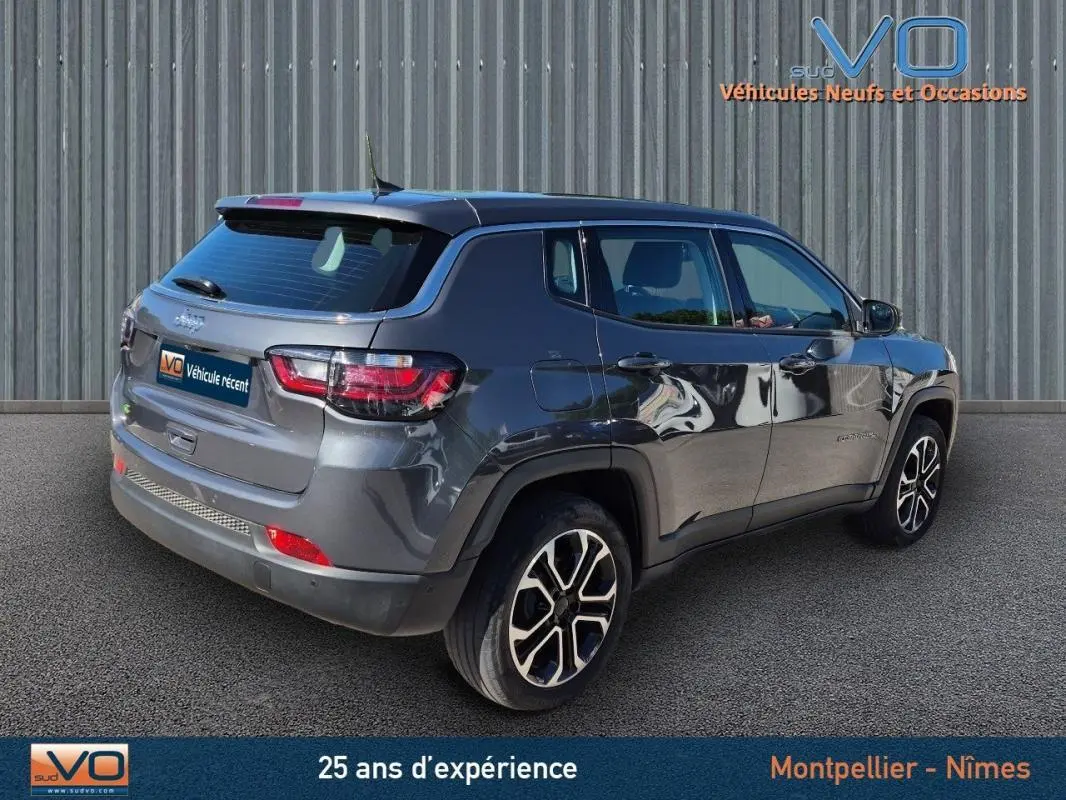 Jeep Compass gris 3/4 arrière droit, jantes alliage 18 pouces, feux LED et rétroviseurs électriques rabattables visibles.