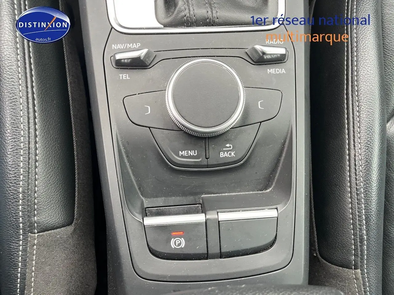 Vue rapprochée de la console centrale noire de l'Audi Q2 2018 avec commandes multimédia et frein à main électrique.