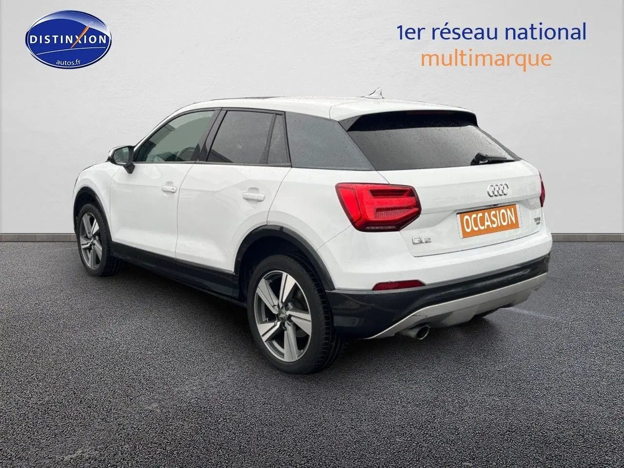 Vue 3/4 arrière droite d'un Audi Q2 blanc Ibis avec jantes alliage 18 pouces et vitres surteintées.