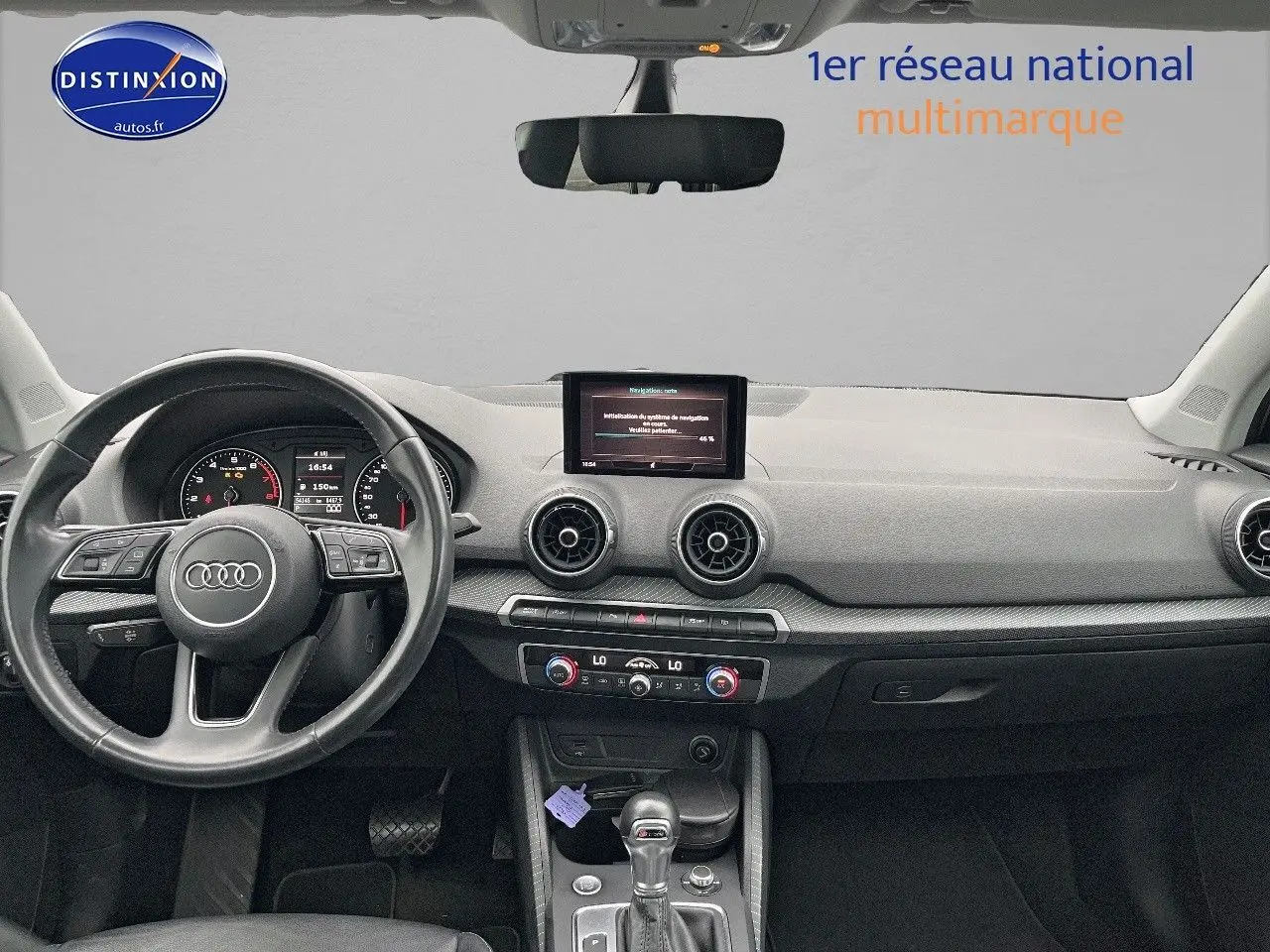 Vue intérieure avant de l'Audi Q2 2018 avec tableau de bord noir, volant cuir multifonction et écran central.