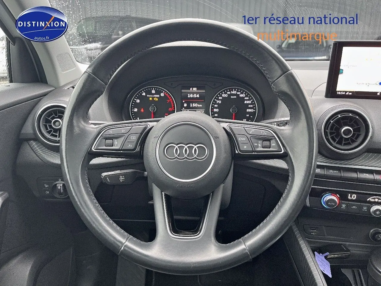 Vue centrée sur le volant en cuir noir de l'Audi Q2 2018 avec tableau de bord et écran multimédia visibles.