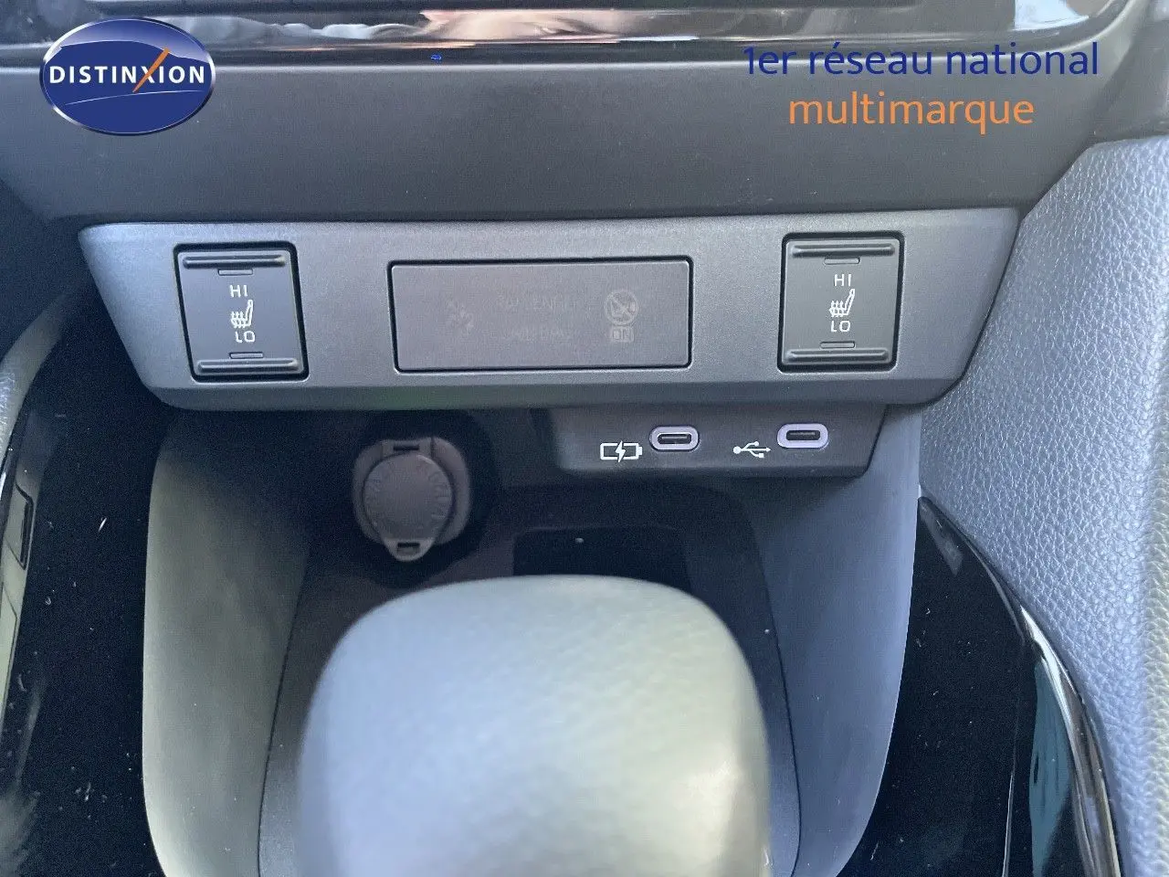 Détail de la console centrale de la Toyota Yaris Hybrid 2025 montrant les commandes de sièges chauffants et ports USB.