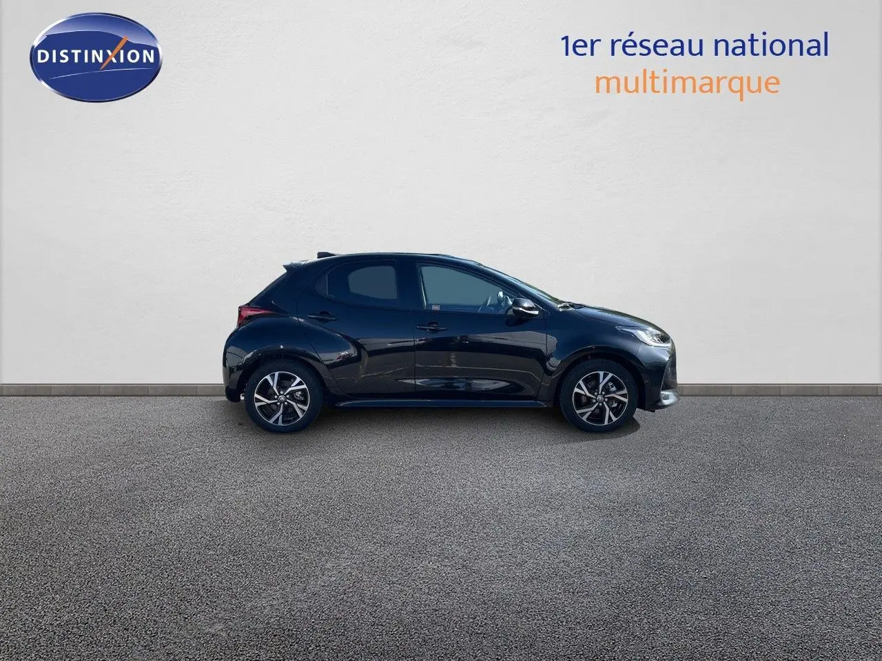 Profil droit d'une Toyota Yaris Hybrid 116ch Design noir métal 2025 avec jantes alliage bicolores sur fond neutre.