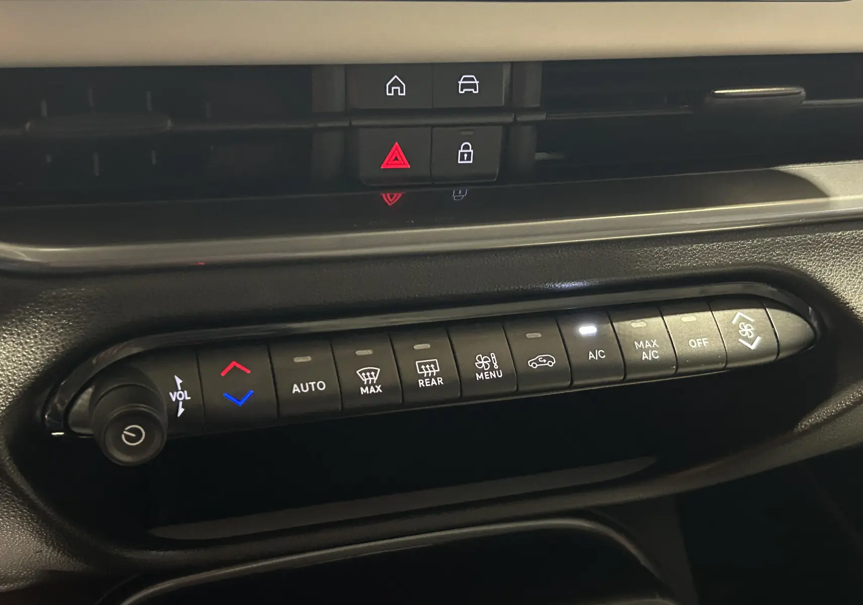 Panneau de commandes climatisation et audio de la FIAT 600 Hybrid 2024, boutons rétroéclairés sur tableau de bord noir.