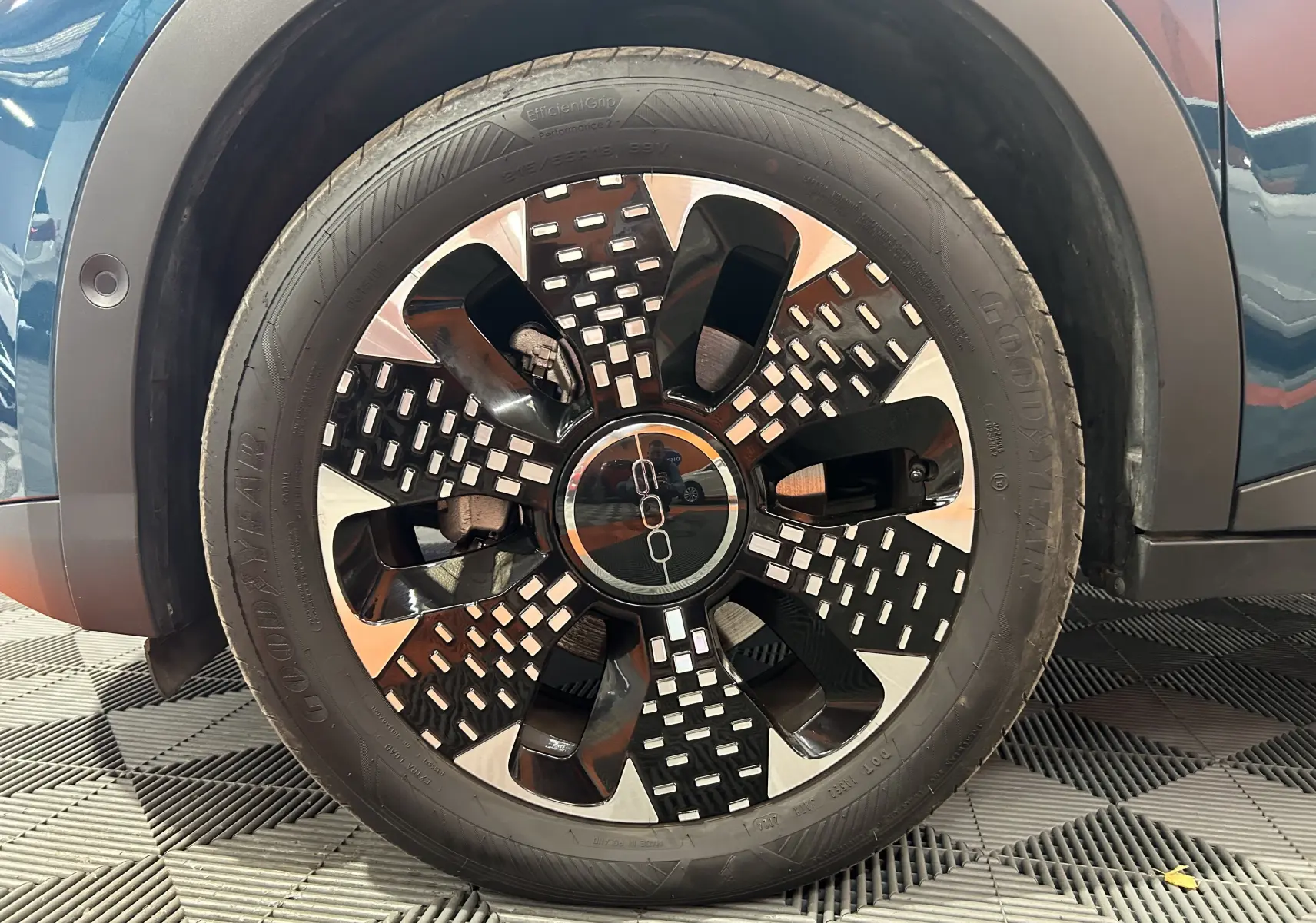 Gros plan sur la roue avant gauche d'une FIAT 600 Hybrid 2024 bleu, avec jante noire et argentée au design moderne.