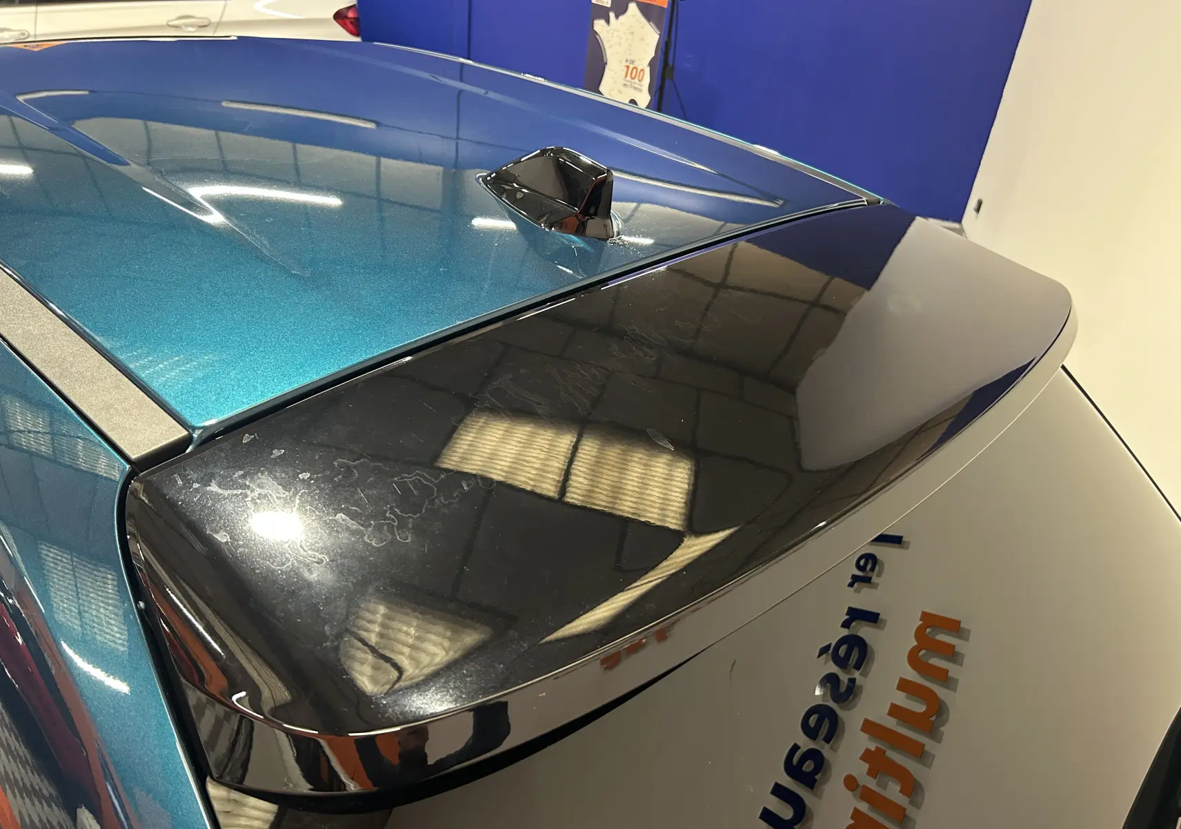 Vue arrière en plongée du toit bleu métallisé et du hayon noir brillant de la FIAT 600 Hybrid 2024 avec antenne shark fin.