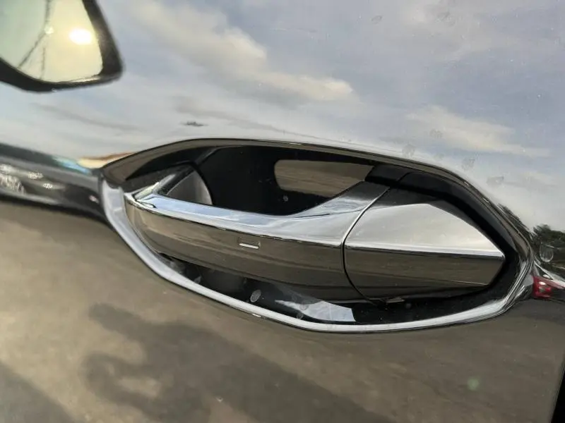 Poignée de porte chromée en gros plan sur la portière noire métallisée d'un Audi Q3 2026.