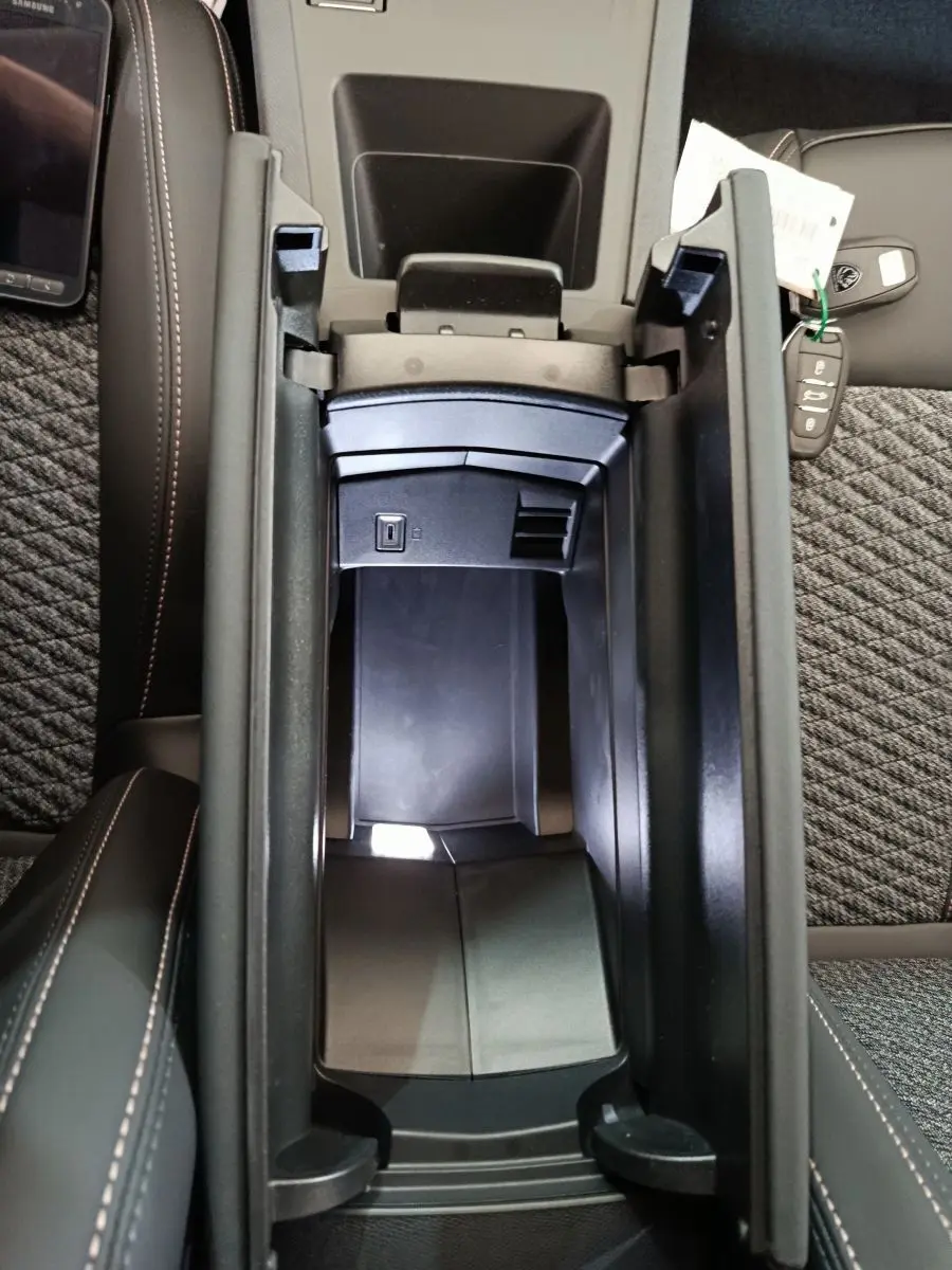 Vue plongeante sur l'accoudoir central ouvert de la Peugeot 308 gris foncé, avec prise USB visible et clé de voiture posée.