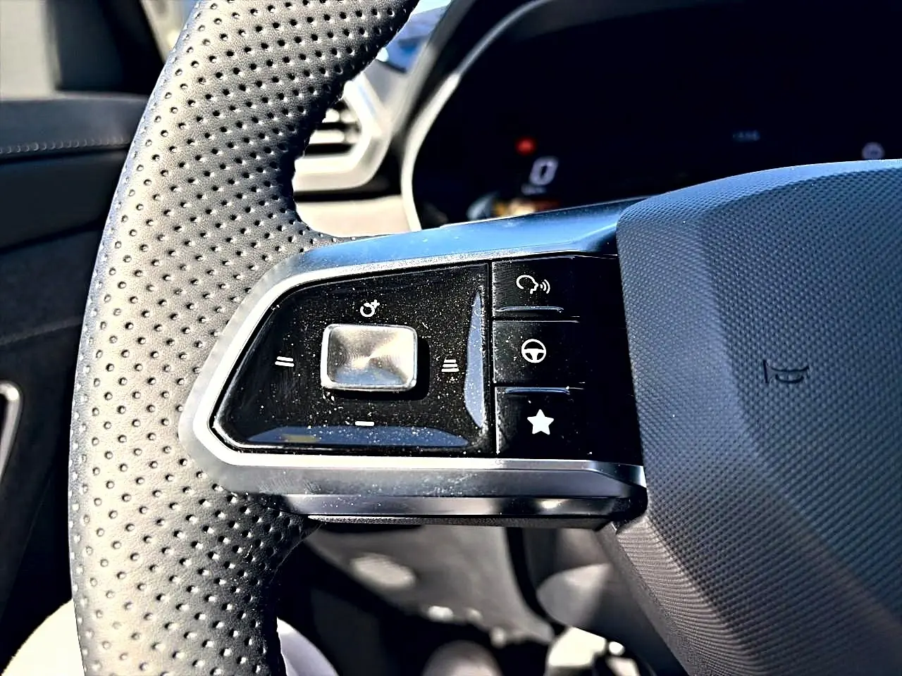 Gros plan sur les commandes gauche du volant perforé noir du MG MOTOR ZS 1.5 hybrid 197 standard 2026.