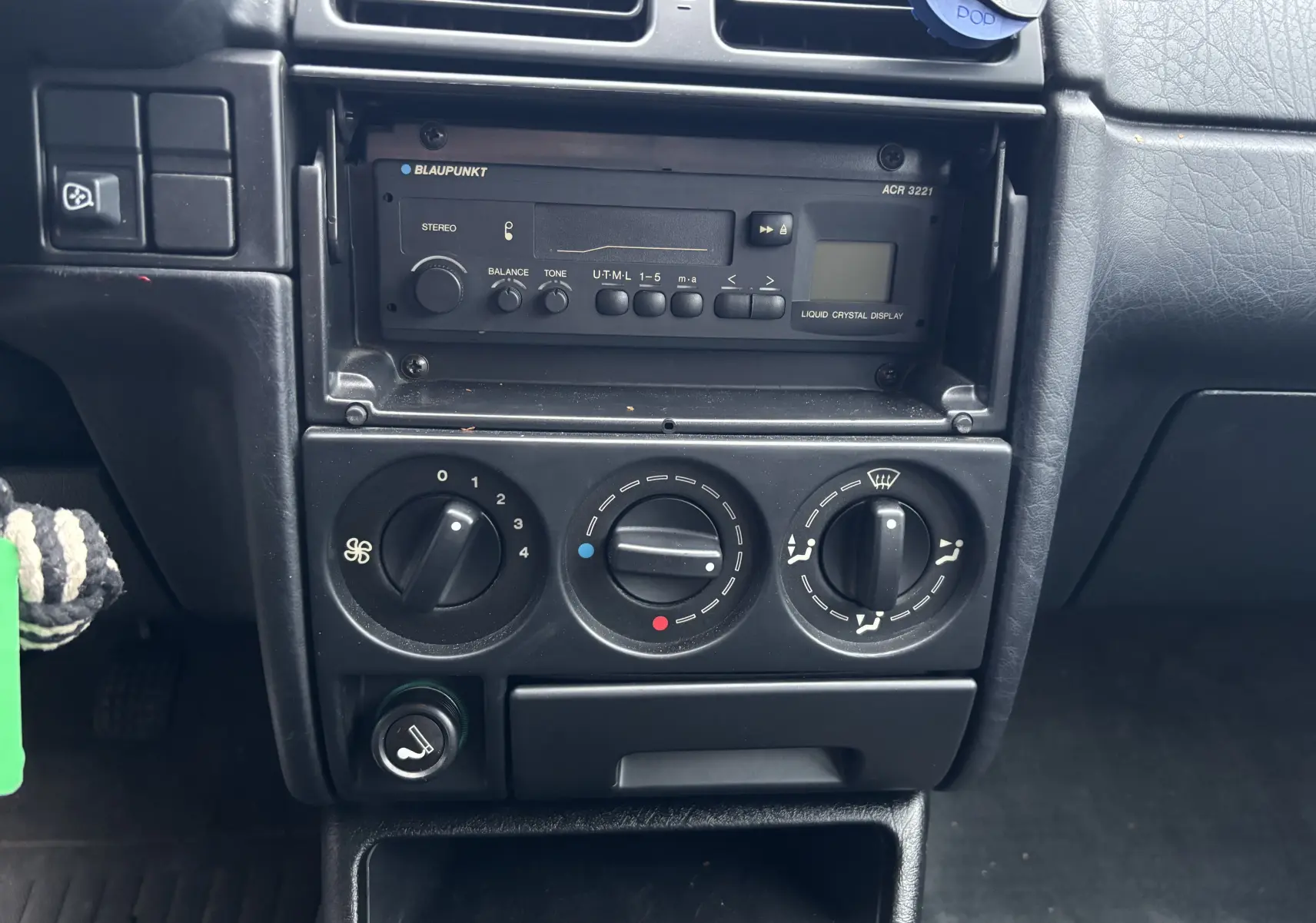 Gros plan sur la console centrale d'une Citroën ZX gris 1992, montrant autoradio Blaupunkt et commandes de climatisation.