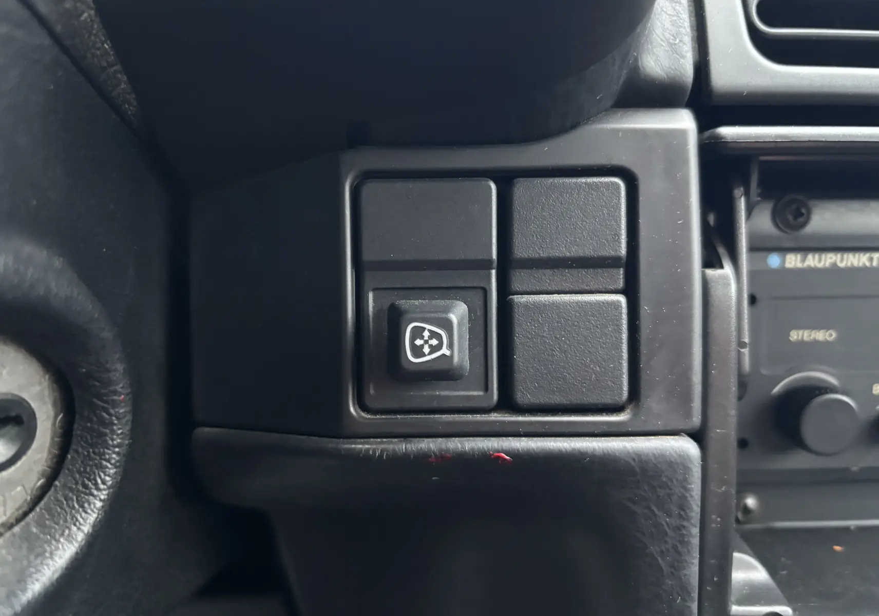 Gros plan sur l'interrupteur de dégivrage de lunette arrière dans l'habitacle d'une Citroën ZX gris de 1992.