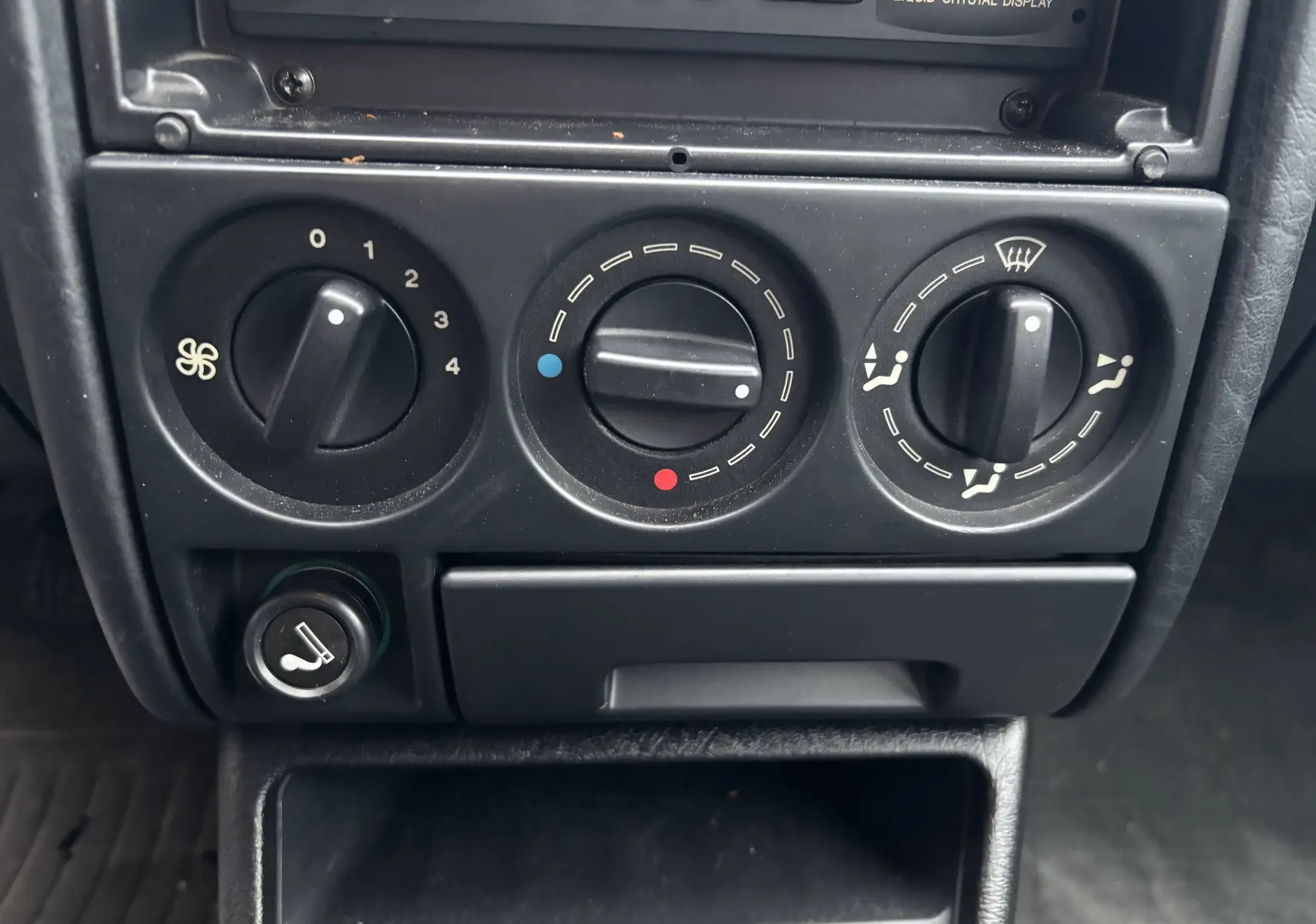 Gros plan sur les commandes de chauffage et ventilation noires du tableau de bord d'une Citroën ZX gris 1992.