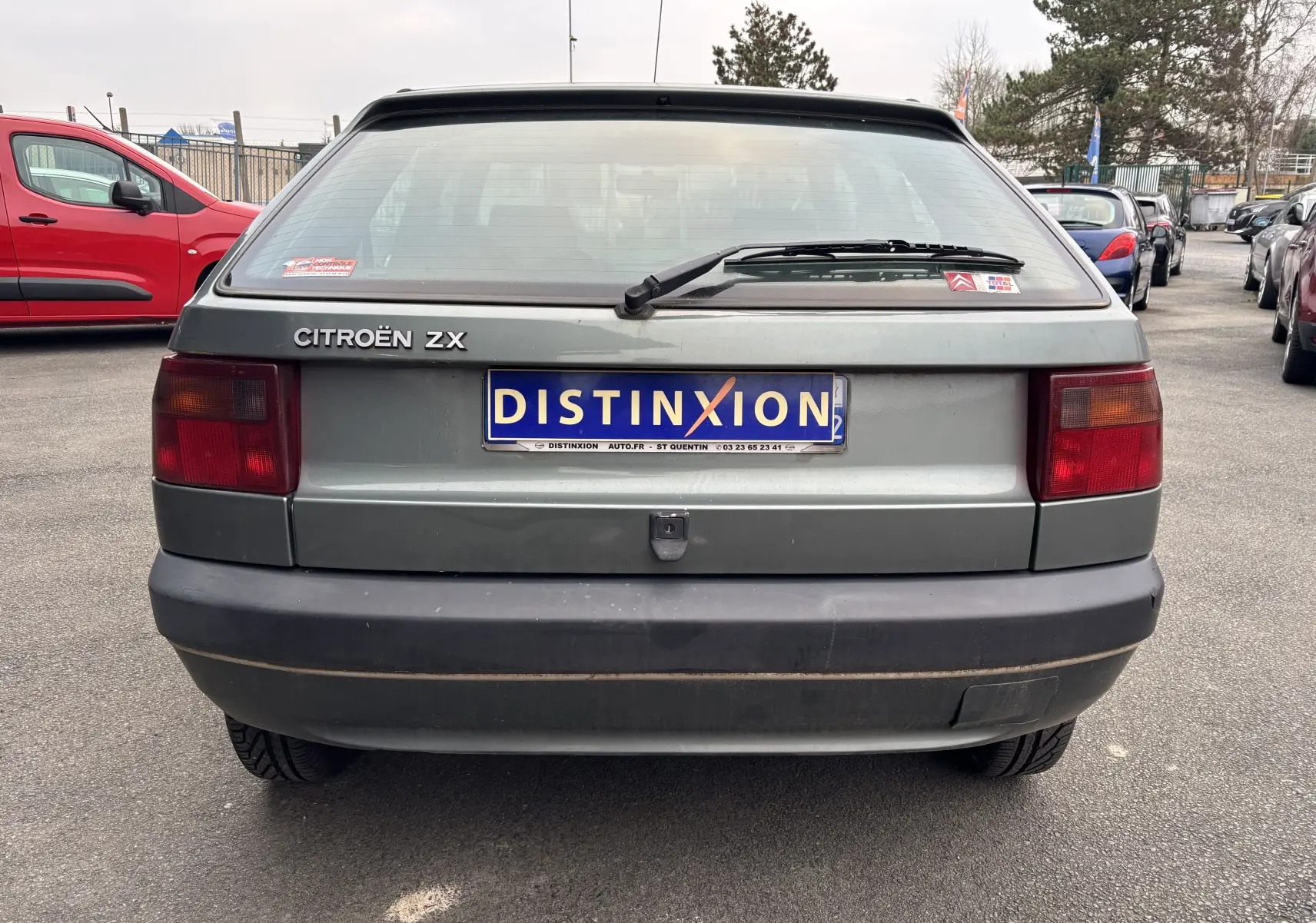 Vue arrière d'une Citroën ZX gris 1992 avec plaque Distinxion et feux arrière rectangulaires rouges.