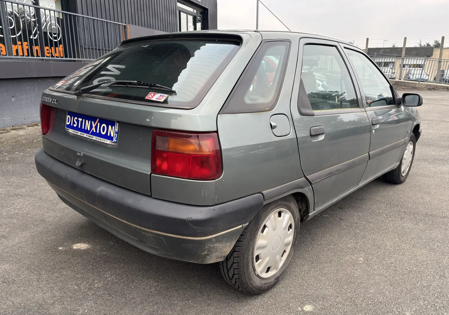 Vue 3/4 arrière droite d'une Citroën ZX gris 1992 avec hayon et feux arrière rectangulaires rouges et orange.