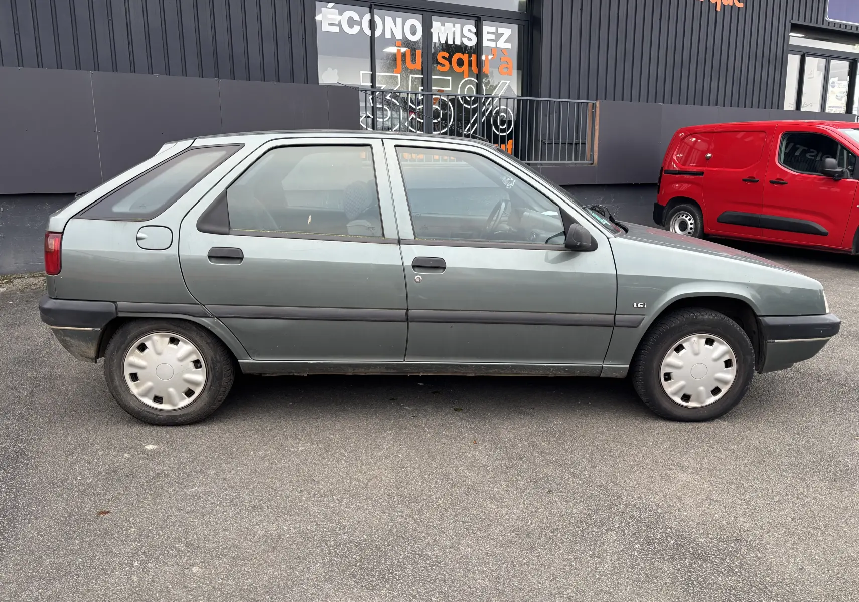 Profil côté gauche d'une Citroën ZX gris 1.6i 89CV de 1992 avec jantes acier et rétroviseurs noirs.