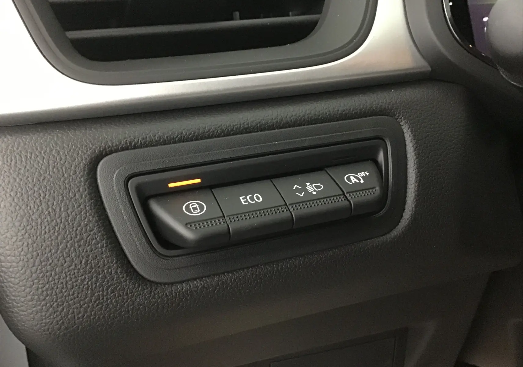 Gros plan sur les boutons de commande du tableau de bord du Renault Captur 2025, avec témoin orange allumé.