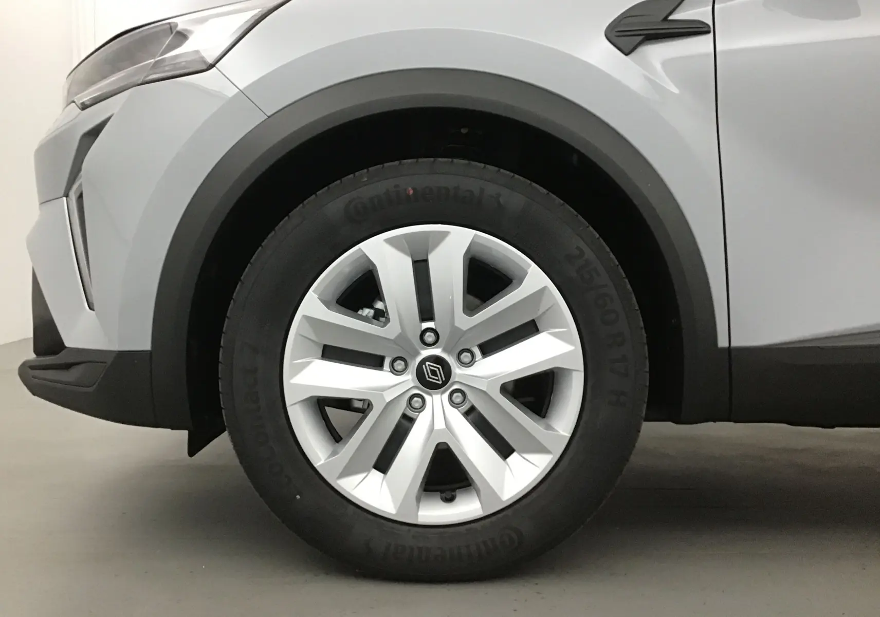 Gros plan sur la roue avant gauche du Renault Captur 2025 gris Rafale avec jante alliage et détail noir sur l'aile.