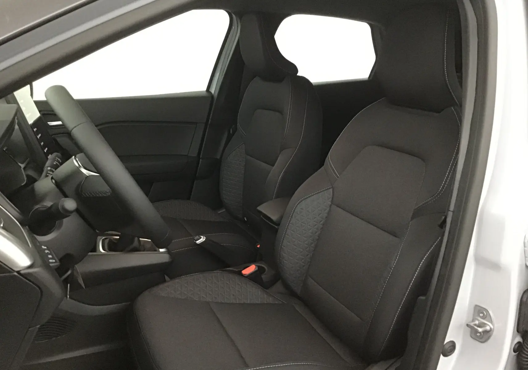 Vue intérieure côté conducteur du Renault Captur 2025, sièges noirs avec surpiqûres et volant multifonction.