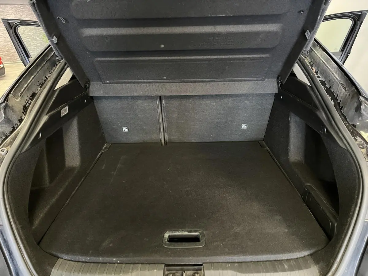 Coffre ouvert vu de l'arrière d'un Renault Arkana noir, montrant le plancher de coffre et les côtés garnis.